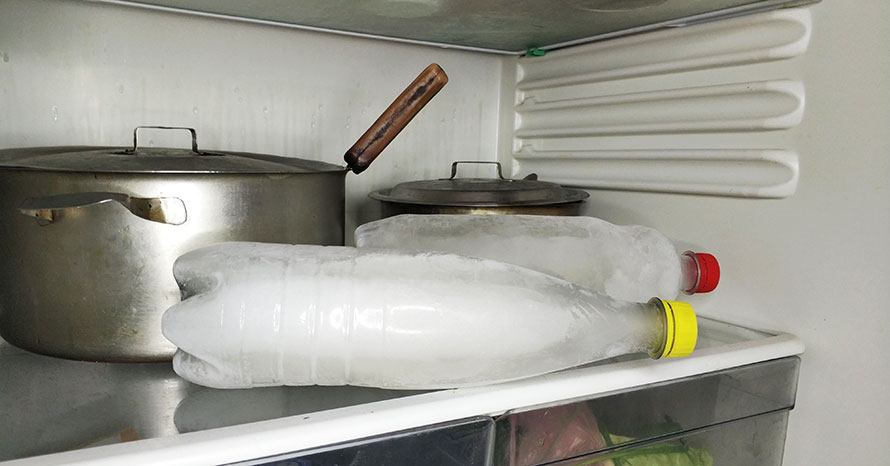 Бутилка з замороженою водою у холодильнику